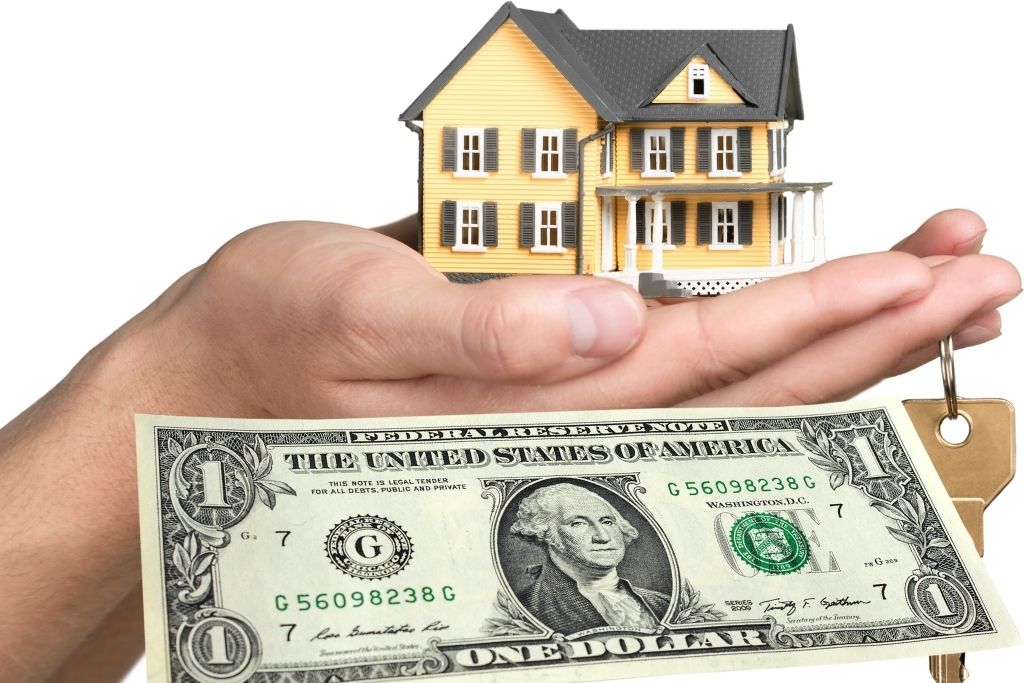 hands holding a miniature house and key with a dollar in front