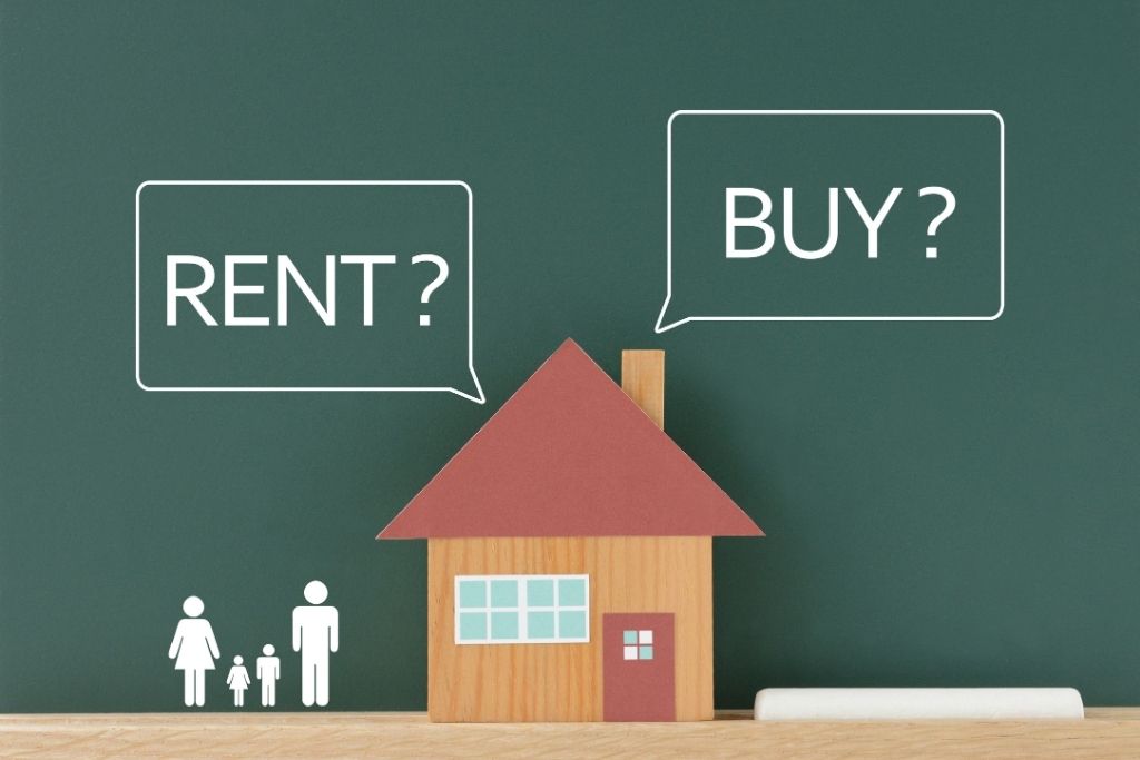 Wooden toy house with chalk text bubbles asking "RENT?" and "BUY?" and stick figures of a family underneath.
